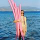 Woman holding pink plastic tubes in the ocean.